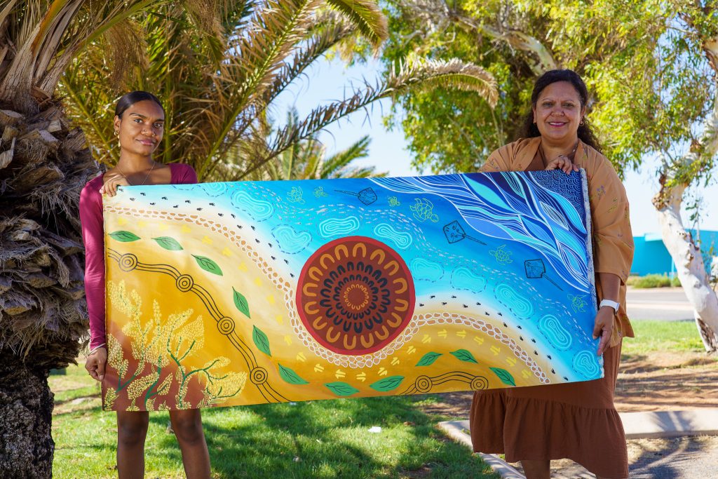 Theonie McKenna and Devinia Wainwright holding up a piece of art that reflects the Carnarvon Common Ground Project