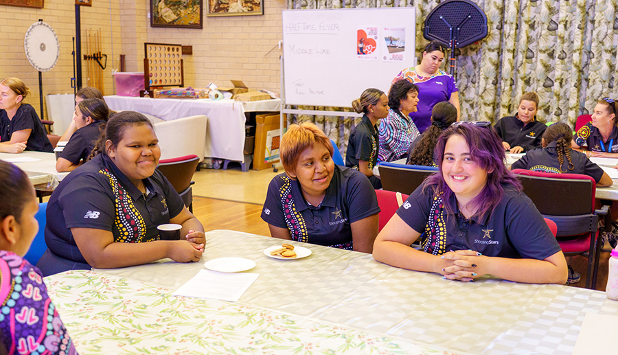 Three girls from Carnarvon Shooting stars sitting at a table for a workshop